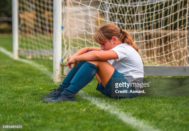 ung flicka fotbollsspelare sitter på fältet efter träning - förödmjukelse bildbanksfoton och bilder