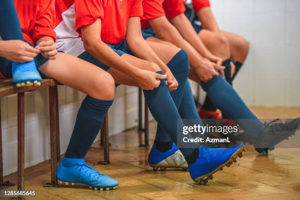 boy footballers putting on socks and shoes before practice - studded footwear stock pictures, royalty-free photos & images