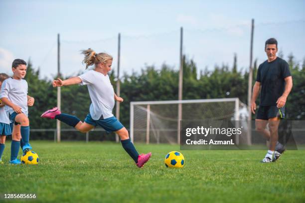 atletische 7 jaar oude voetballer die schoppen op gebied oefent - sportoefening stockfoto's en -beelden