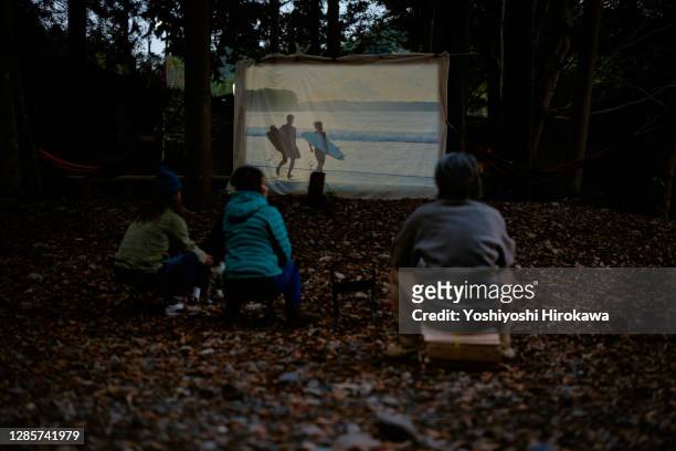 people watching outdoor movies in front of wooden camp hut - film and television screening stock pictures, royalty-free photos & images