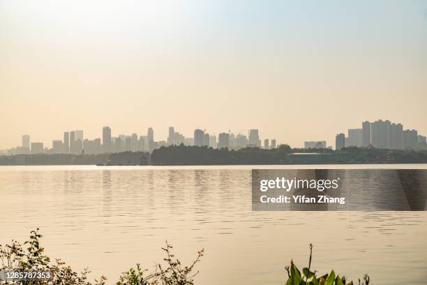 a distant perspective of wuhan city with reflection on the east lake at sunset - east lake stock pictures, royalty-free photos & images