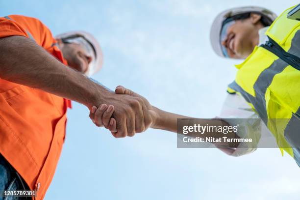 low angle view of construction site manager and engineer greeting each other. teamwork working together. - partnership teamwork build stockfoto's en -beelden