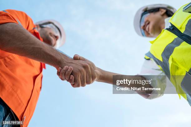 low angle view of construction site manager and engineer greeting each other. teamwork working together. - civil engineering stock pictures, royalty-free photos & images