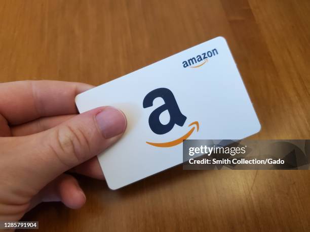 Person holding a white Amazon gift card featuring the Amazon logo in San Ramon, California, USA, November 8, 2020.