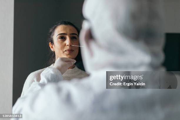 arzt in schutzarbeitskleidung unter nasenabstrich test von jungen frau - pcr gerät stock-fotos und bilder