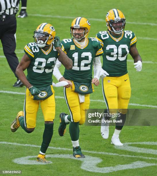 Marquez Valdes-Scantling, Aaron Rodgers and Jamaal Williams of the Green Bay Packers react as they watch the replay board as they come off of the...