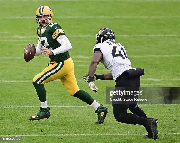 Aaron Rodgers of the Green Bay Packers looks for a receiver under pressure from Josh Allen of the Jacksonville Jaguars at Lambeau Field on November...