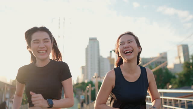 Two Asian woman jogging and checking her smart watch at public park