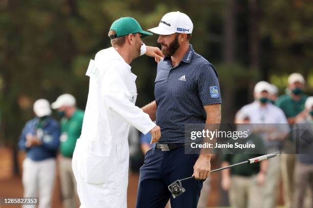 Dustin Johnson of the United States celebrates with caddie Austin Johnson on the 18th green after winning the Masters at Augusta National Golf Club...