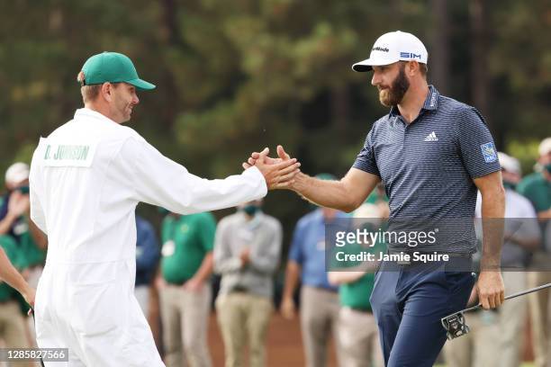 Dustin Johnson of the United States celebrates with caddie Austin Johnson on the 18th green after winning the Masters at Augusta National Golf Club...