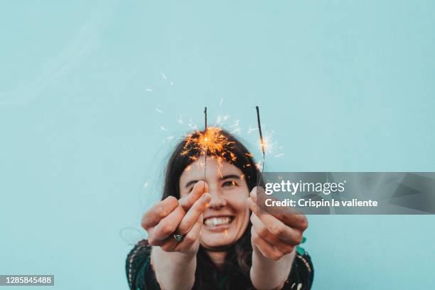 girl with two sparklers smiling on blue background - new years resolutions stock-fotos und bilder