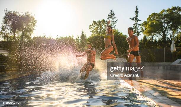 friends running and jumping into swimming pool - poolside stock pictures, royalty-free photos & images