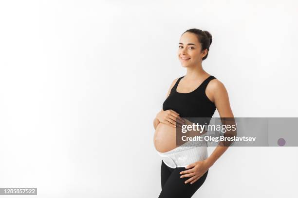 pregnant happy smiling woman with naked abdomen in support bandage medical corset. - orthopedic corset stock pictures, royalty-free photos & images