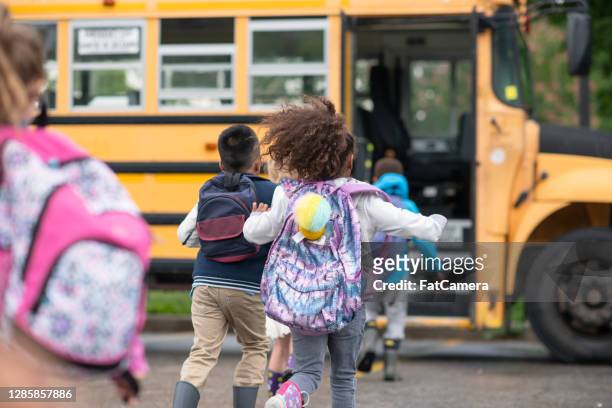 kids getting onto the school bus - minibuses stock pictures, royalty-free photos & images