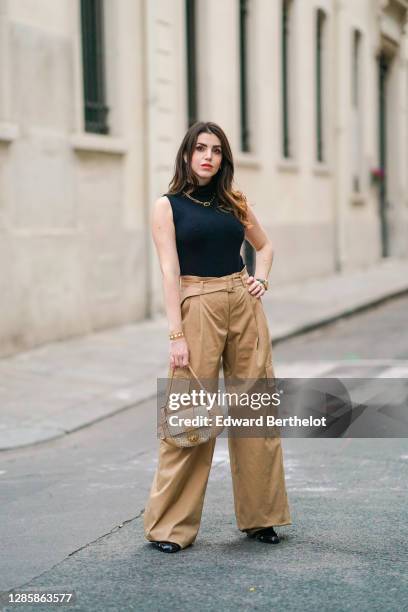 Sara Carnicella wears a golden necklace from APM Monaco, a black turtleneck sleeveless pullover / body from Wolford, beige pale brown flared pants...