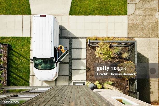 overhead view of female delivery driver returning to van after delivering package to home - white van stock pictures, royalty-free photos & images