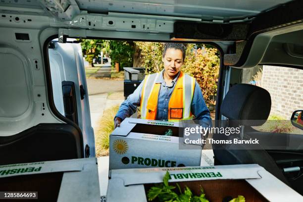 female delivery driver removing fresh organic produce box from van during delivery at home - food van stock pictures, royalty-free photos & images