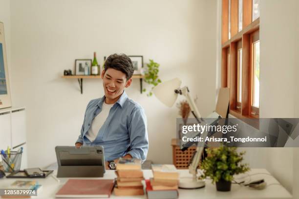 handsome guy video call with his friend. - asian man home laptop stock pictures, royalty-free photos & images