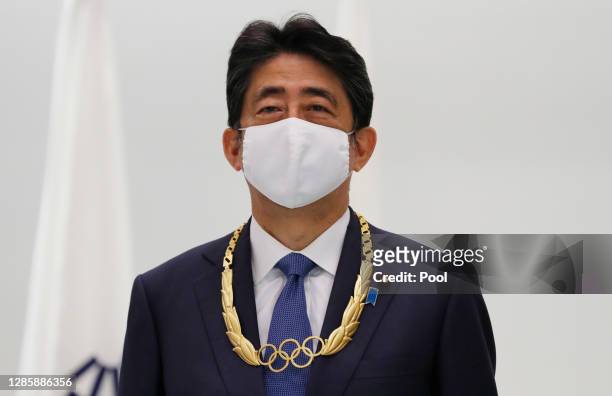 Japan's former Prime Minister Shinzo Abe wearing the Olympic Order presented by IOC poses at a photo session after the ceremony at Japan Olympic...