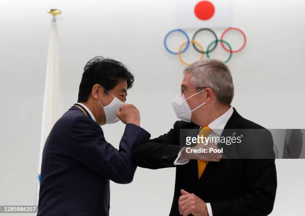 Japan's former Prime Minister Shinzo Abe and Thomas Bach, President of the International Olympic Committee , elbow bump after a ceremony to present...