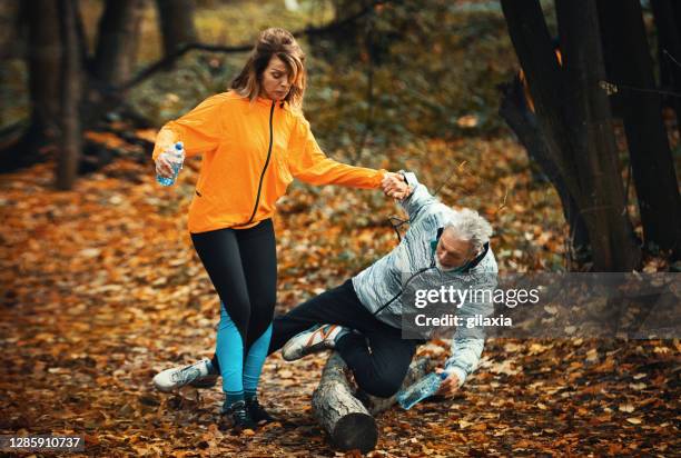 senior paar joggen in een bos en vervolgens ... - val stockfoto's en -beelden