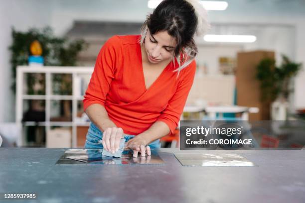 woman putting ink on some metallic plates - stock photo - stamp collecting stock-fotos und bilder