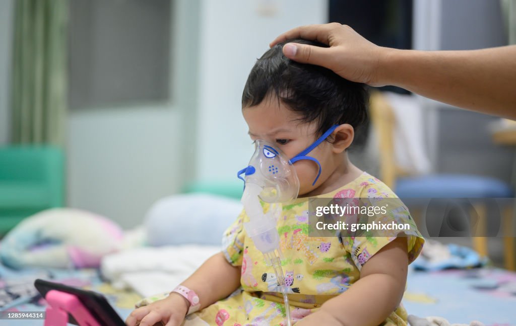 Asiatisches Baby war als Respiratory Syncytial Virus (RSV) im Kinderkrankenhaus krank. Thai kleines Mädchen mit Inhalator mit Medikamenten zum Aufhören husten und Grippe.