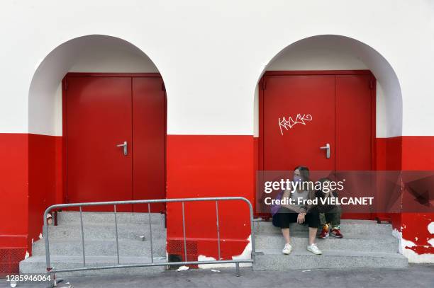 Une femme avec un masque et un enfant assis sur un escalier attendent dans la rue le 26 avril 2020, Paris, France.