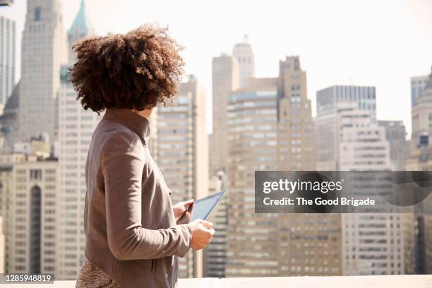 businesswoman on rooftop holding a tablet computer - businesswoman nyc stockfoto's en -beelden