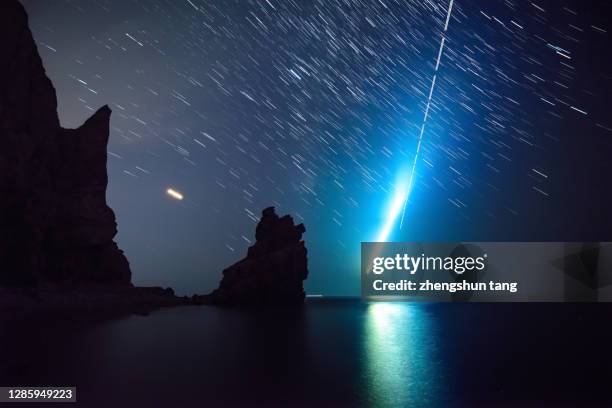 comet reflected in the sea at night with a star trail overhead. - comet stock pictures, royalty-free photos & images