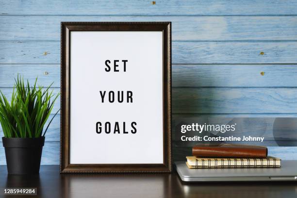 set your goals. wood frame and potted plant on working desk. - picture frame desk stock pictures, royalty-free photos & images