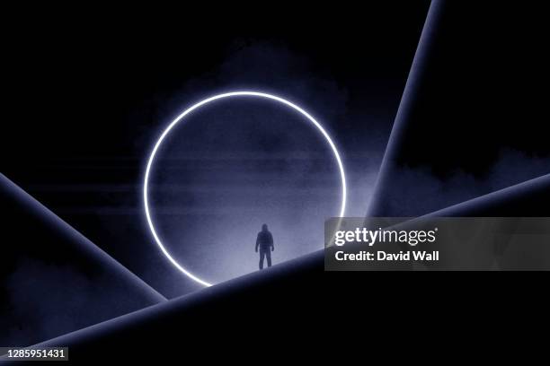 a minimal science fiction edit of a hooded silhouette of a figure of a man standing in front of a glowing portal. - tor konstruktion stock-fotos und bilder