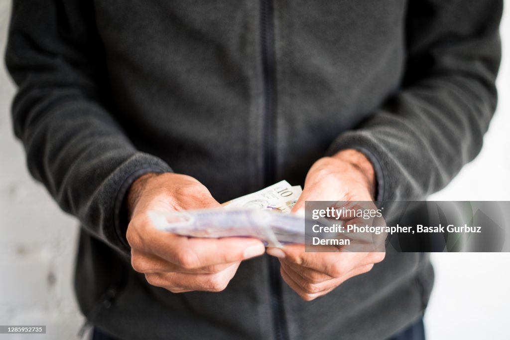 A man holding five and ten pound notes