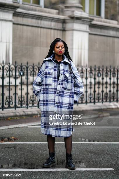 Guest wears a blue and white checked long wool coat with large pockets, black tights, black leather Dr Martens shoes, outside Yohji Yamamoto, during...
