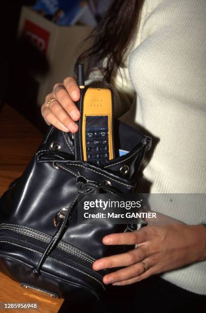 Femme sortant un téléphone portable de son sac à main, circa 1990, France.