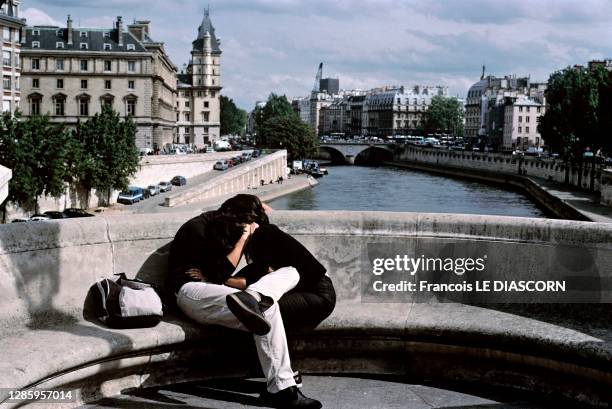 Un couple s'embrasse sur un banc du Pont Neuf