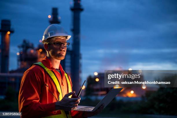 engineering is use notebook check and standing in front of oil refinery building structure in heavy petrochemical industry - man blue background fotografías e imágenes de stock