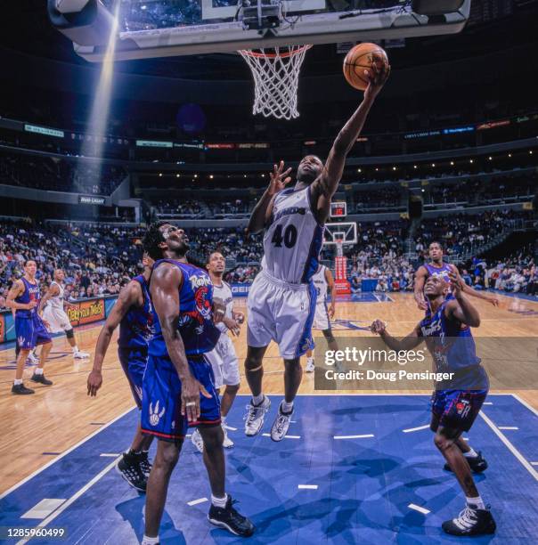 Calbert Cheaney, Shooting Guard for the Washington Wizards makes a one handed lay up to the basket over Dee Brown and Charles Oakley of the Toronto...