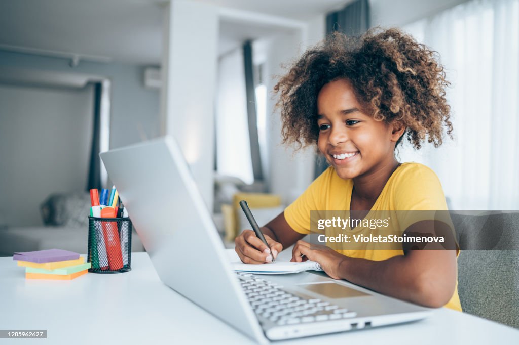 Schoolgirl studying with video online lesson at home.