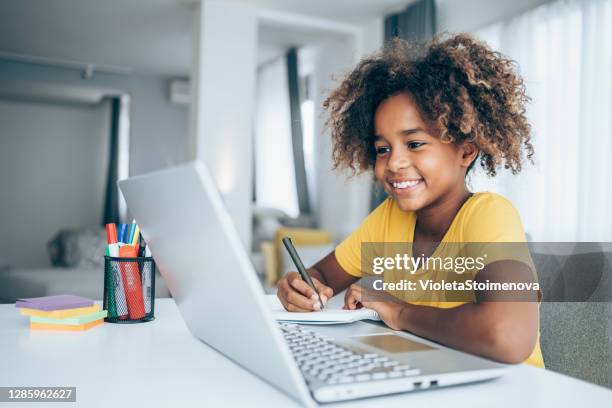 little girl doing her homework schoolgirl studying with video online lesson at home. - girl doing homework stock pictures, royalty-free photos & images