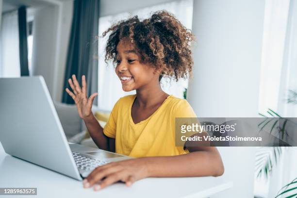 fröhliche mädchen mit videoanruf zu hause. - black girl with computer stock-fotos und bilder