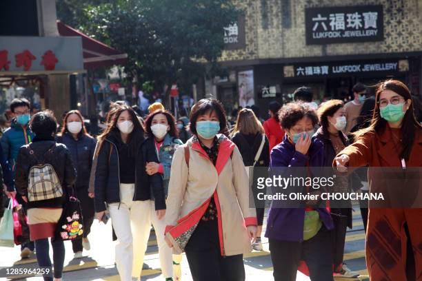 Piétons masqués pour se protéger du virus Corona traversant l'artere commerciale principale du quartier touristique de Causeway Bay le 31 janvier,...