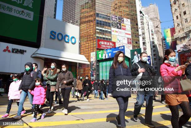 Piétons masqués pour se protéger du virus Corona traversant l'artere commerciale principale du quartier touristique de Causeway Bay le 31 janvier,...