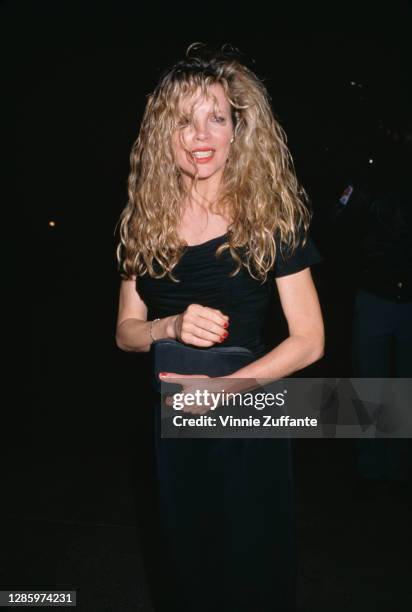 American actress Kim Basinger with shoulder-length blonde hair in a loose perm, wearing a black dress in Los Angeles, California, circa 1990.