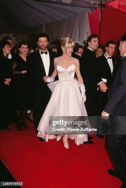 American actor Alec Baldwin and his wife, American actress Kim Basinger wearing a white strapless evening gown, with white evening gloves, attend the...
