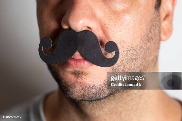 close up of a man wearing a prop black mustache - movember stock-fotos und bilder