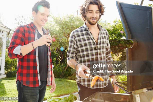 male friends barbecuing at backyard party - garden talking photos et images de collection