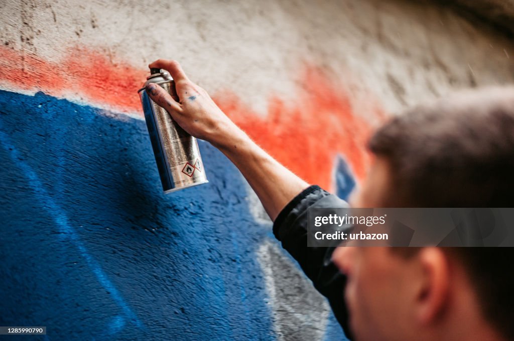 Man painting graffiti on wall