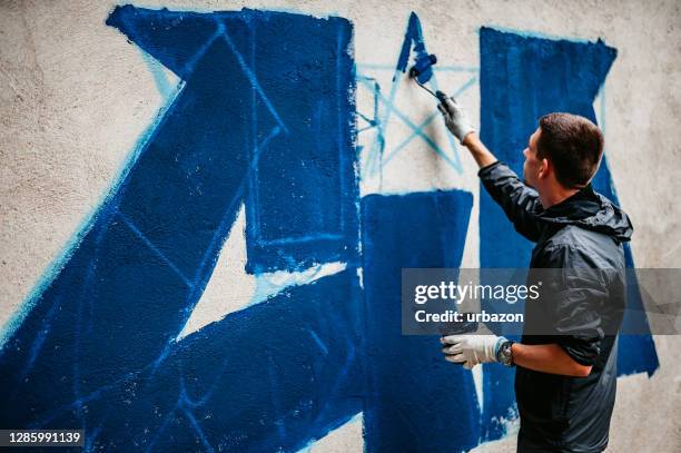 man painting graffiti on wall - street artist stock pictures, royalty-free photos & images