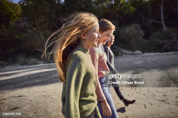 happy girls and woman walking on the beach - girl blowing sand stock-fotos und bilder